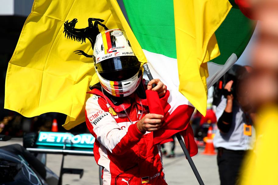 Sebastian Vettel vince il Gran Premio della Malesia. Ecco il pilota tedesco della Ferrari dopo aver tagliato il traguardo con le bandiere dell&#39;Italia e della Ferrari (GETTY IMAGES)